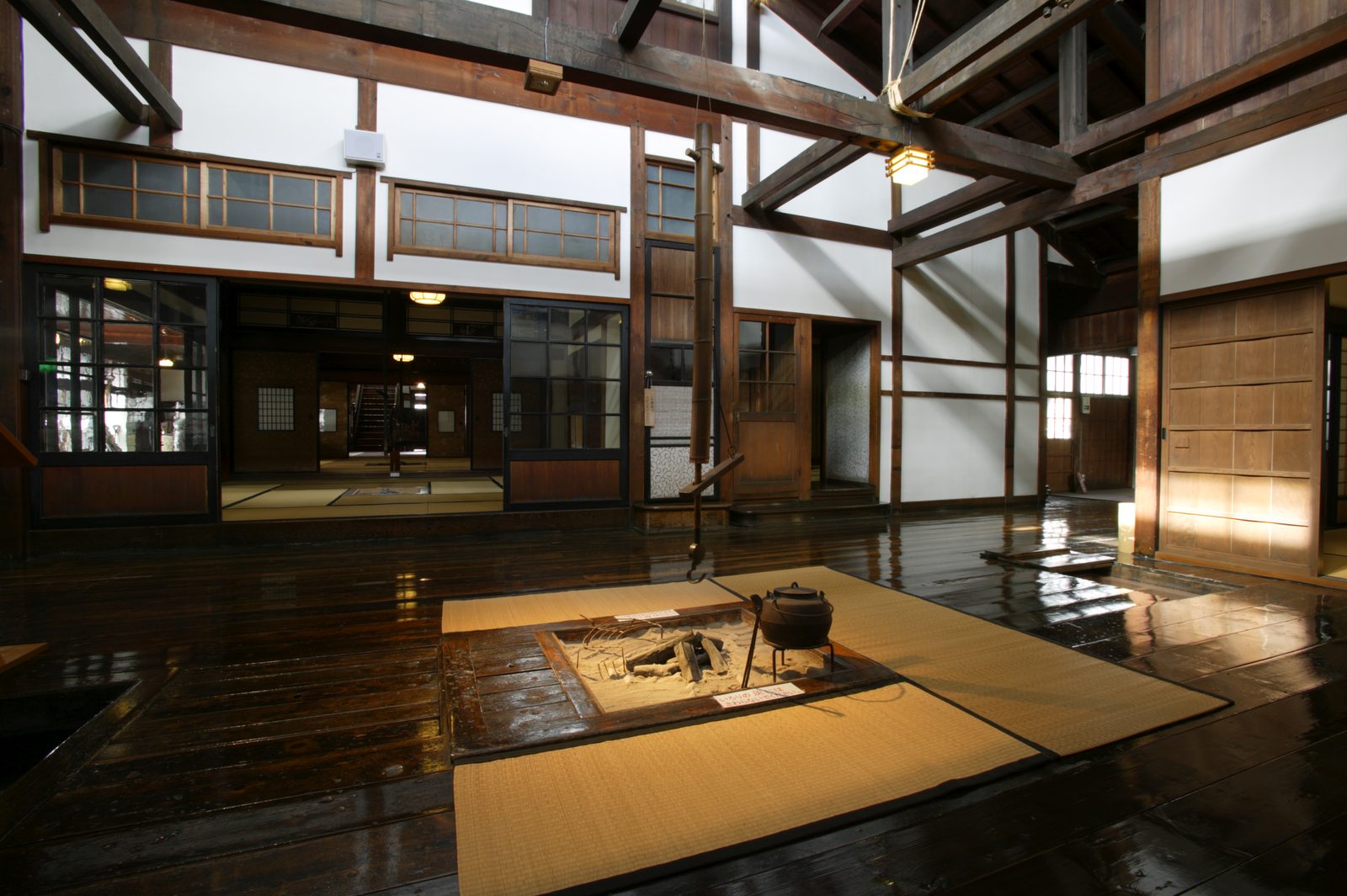 The earthen-floored hall of Shayokan with a sunken hearth and tatami mats under dark timber beams
