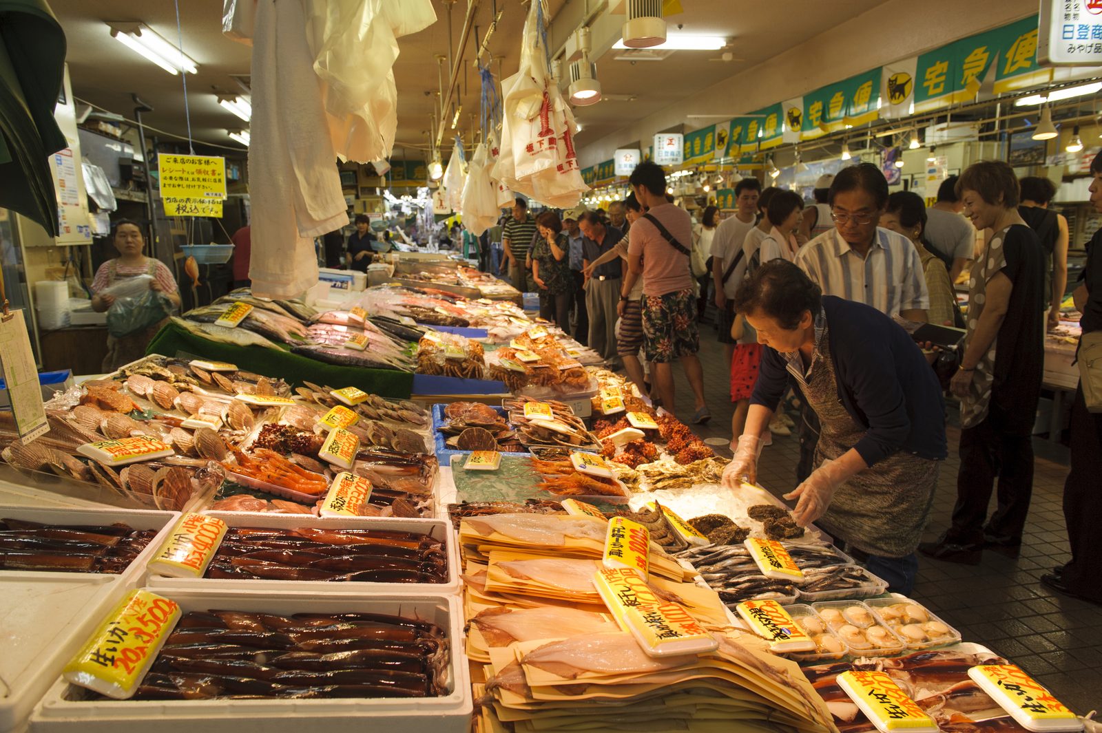Shoppers browsing trays of dried and salted fish at a stall inside Hasshoku Center