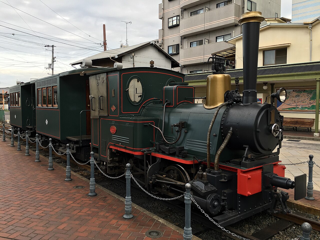 The preserved Botchan Ressha locomotive and its carriages standing at the Dogo Onsen tram terminus, with the town behind.