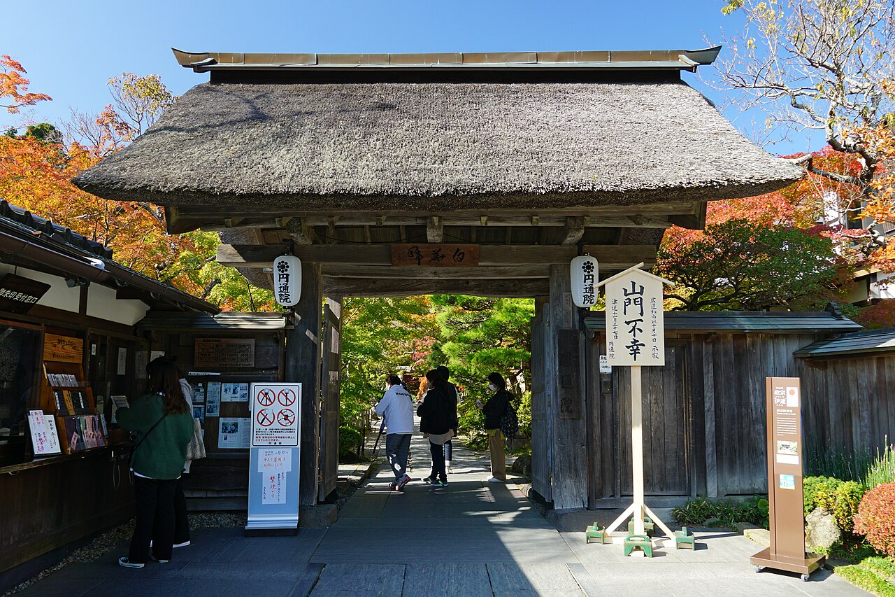 The thatched gate of Entsuin with maples turning red on either side of the entrance path