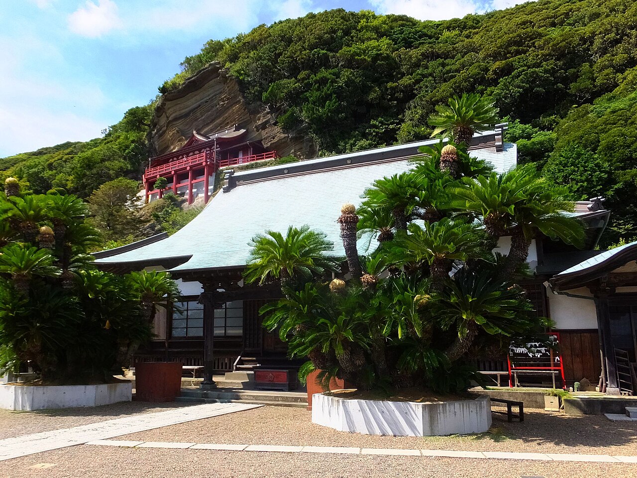 The vermilion hall of Gake Kannon built against the rock face above Daifuku-ji's cycad-lined main hall