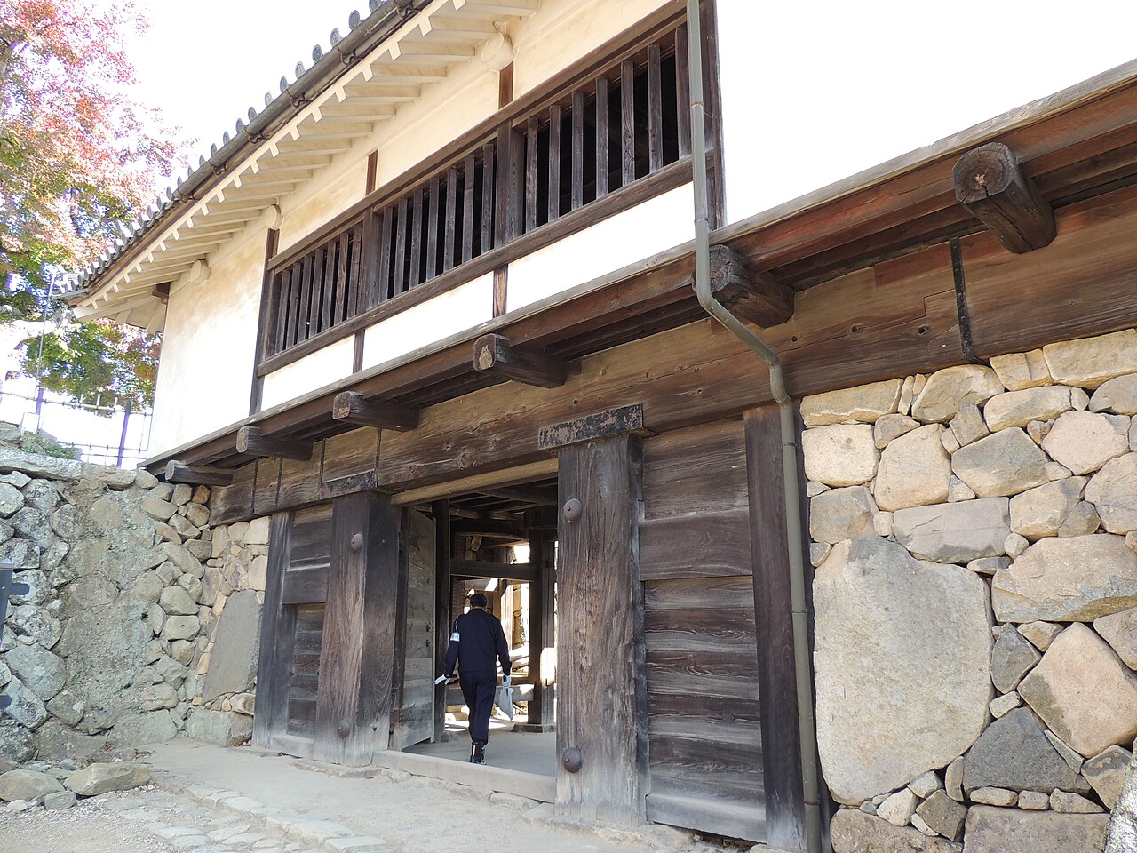 A wooden gate and turret in the grounds of Hikone Castle, above a wall of fitted stone.