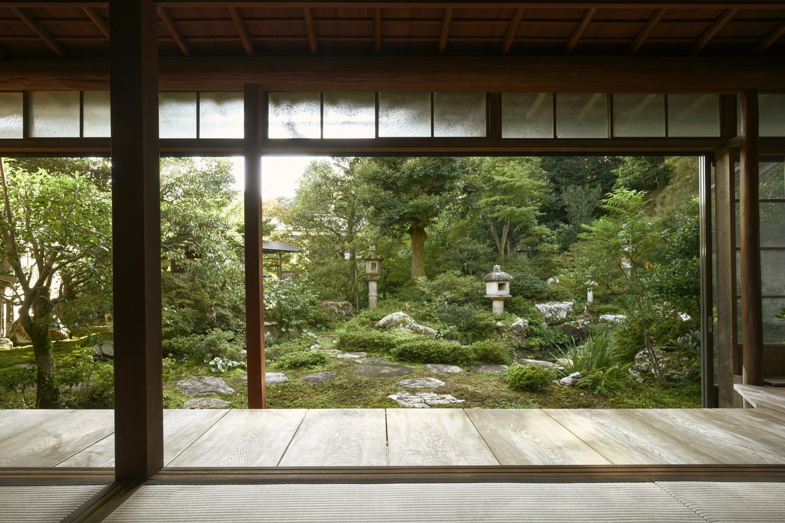 A garden with stone lanterns and moss seen from the wooden veranda of Zorokuen