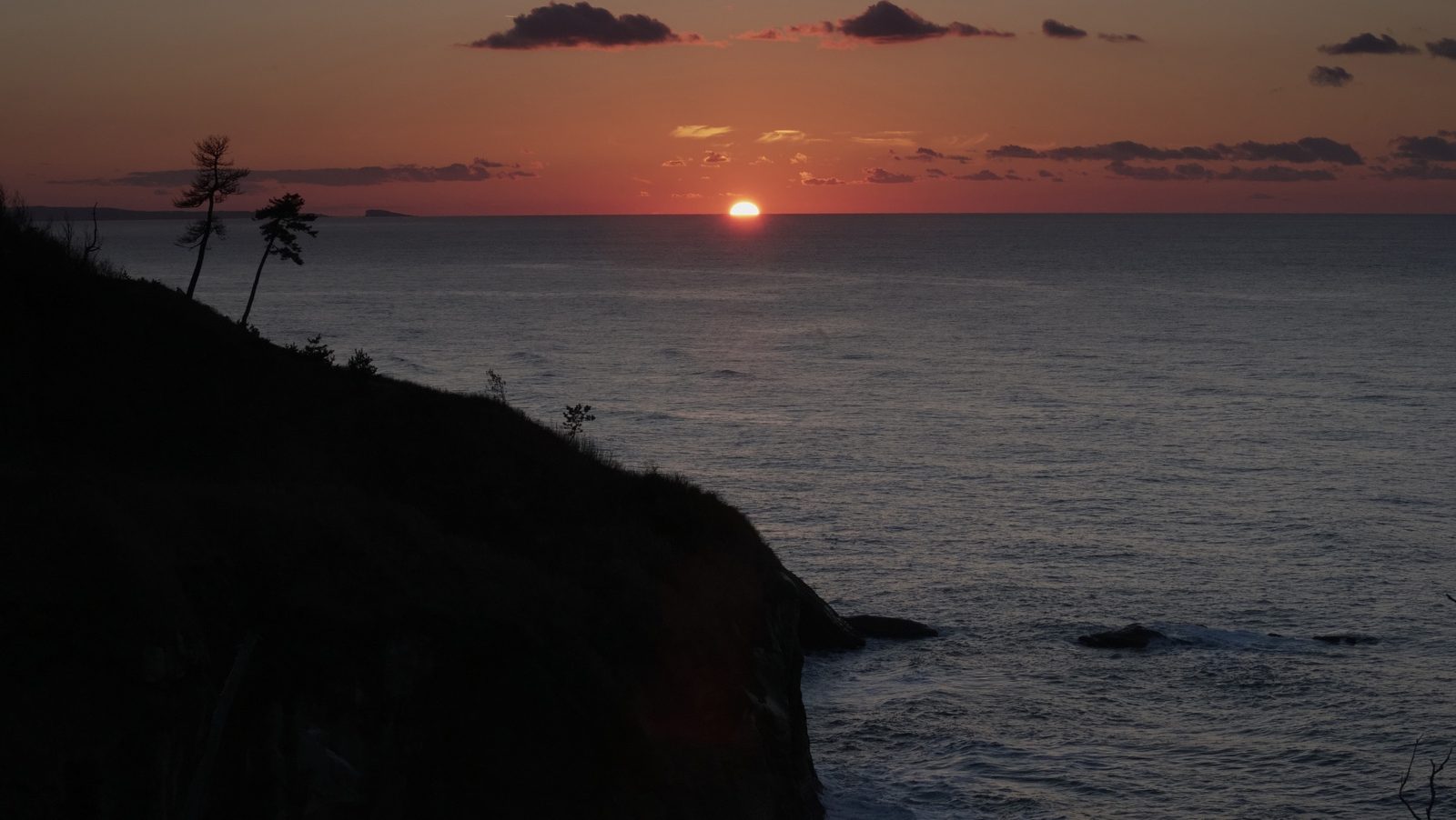 The sun setting over the Sea of Japan beyond the dark headland of Cape Kasa