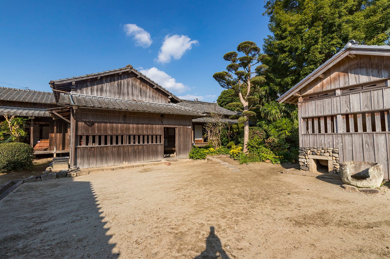 Weathered wooden buildings around a sandy yard at a samurai residence in Izumi Fumoto
