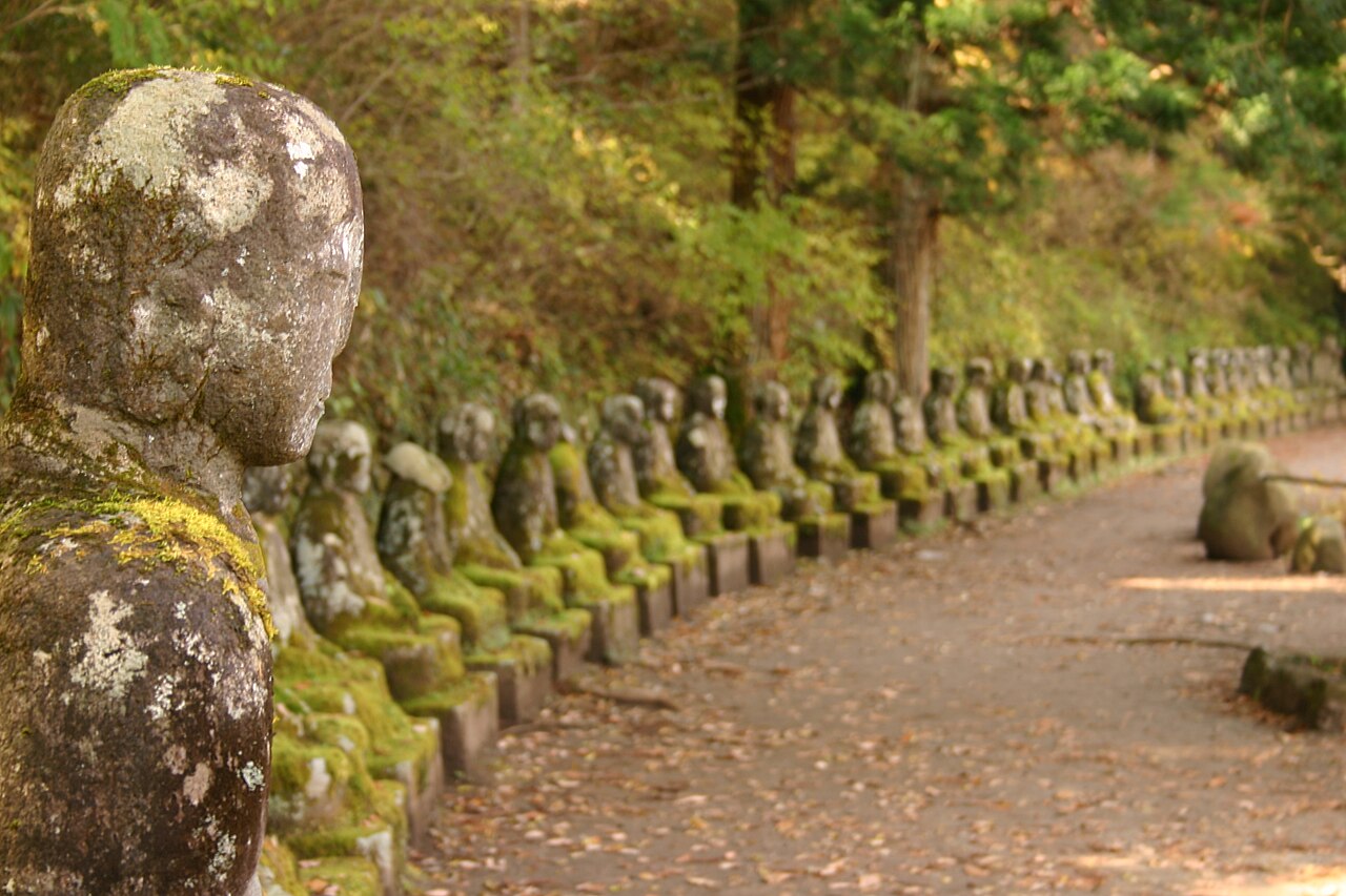 A long row of moss-grown stone Jizo statues beside the walkway at Kanmangafuchi.