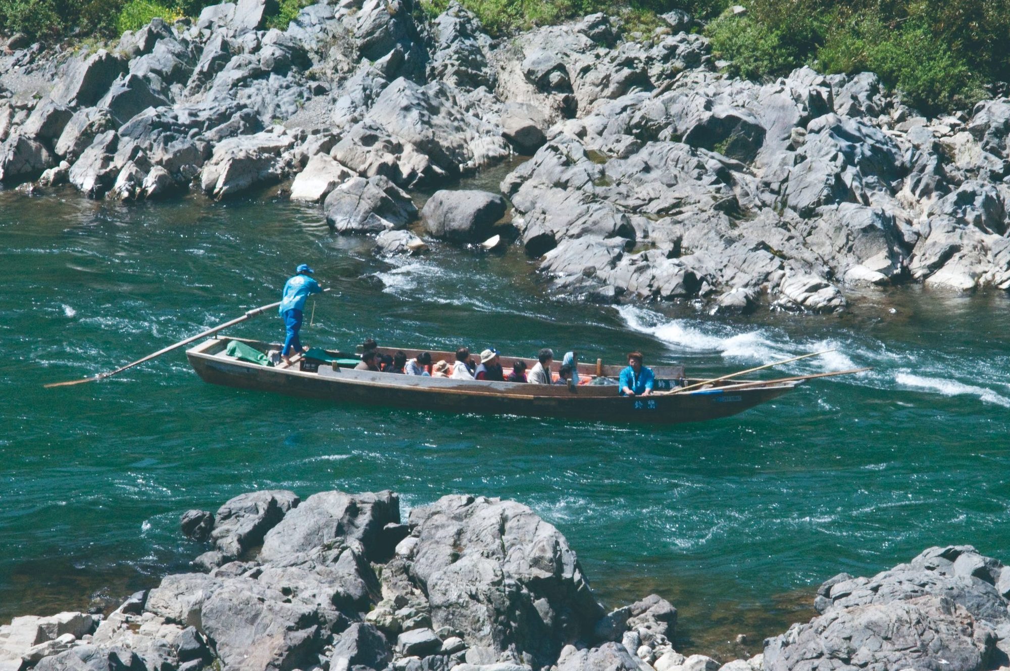 A flat-bottomed boat carrying passengers down the Kuma River near Hitoyoshi