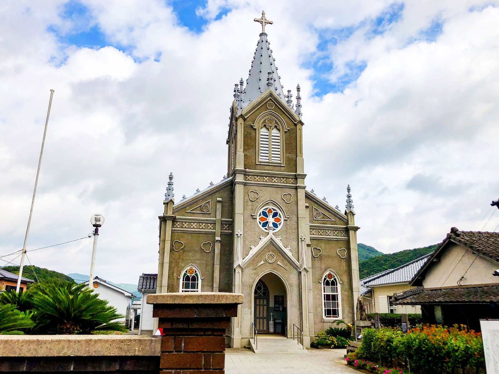 Sakitsu Church's gray stone facade and spire rising above the surrounding houses.