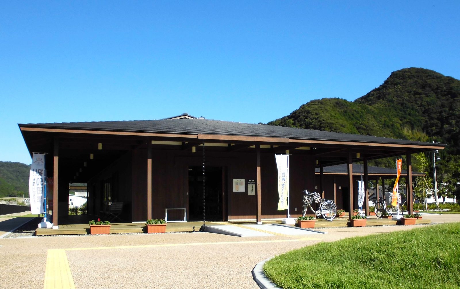 The low wooden Sakitsu Village Guidance Center under green hills.