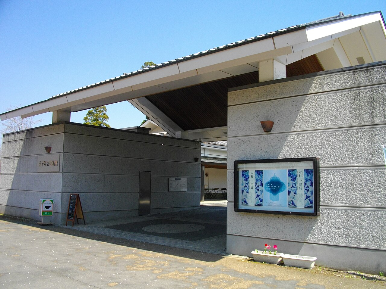 The entrance canopy of the Mashiko Museum of Ceramic Art, with an exhibition poster beside the doorway.