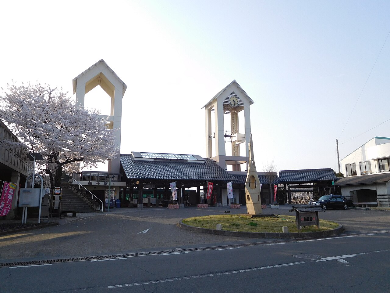 The forecourt of Mashiko Station on the Moka Line, with its clock tower and a cherry tree in blossom.