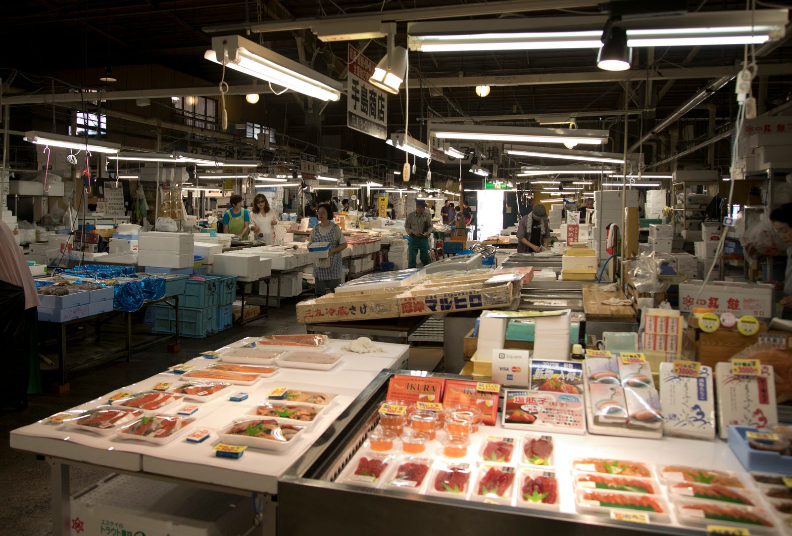 Counters of fresh fish and sashimi inside the Shiogama wholesale seafood market under bright ceiling lights