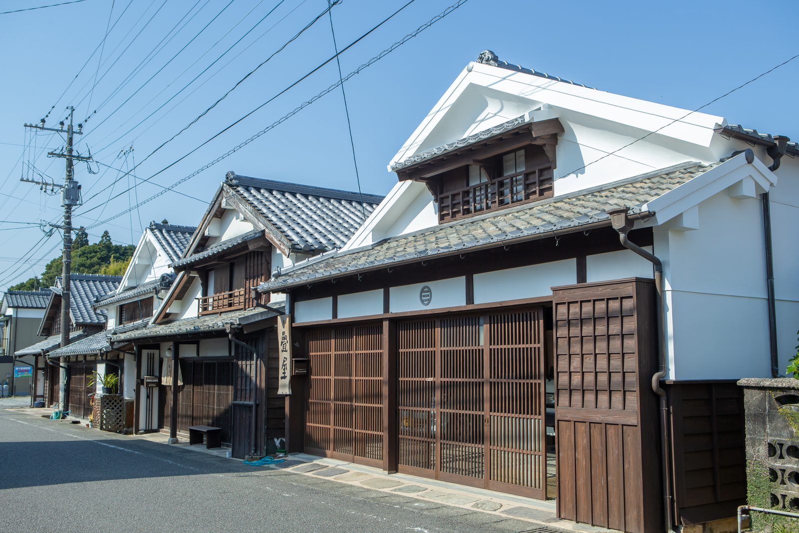A street of white-walled merchant houses with lattice doors lined up along an old town street