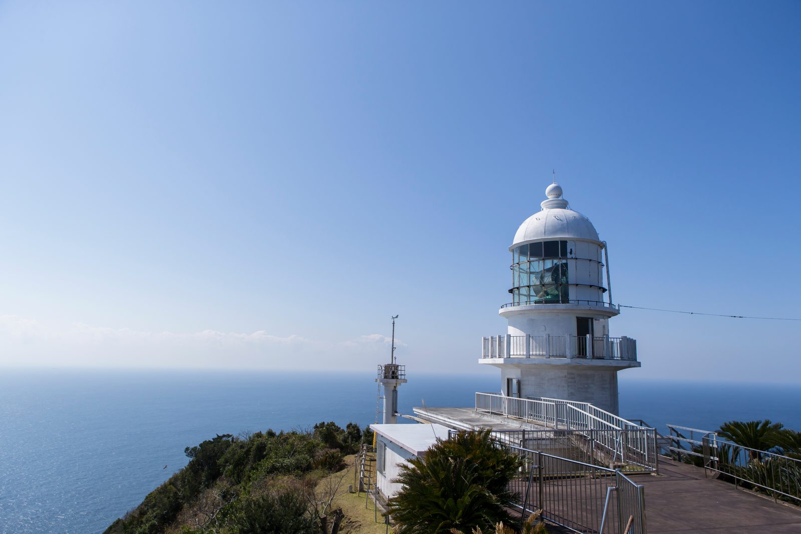 The white Toimisaki Lighthouse on the cape, with the open sea beyond