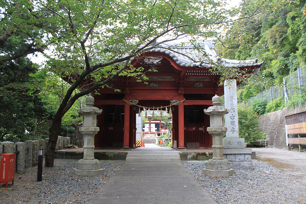 Vermilion Nio gate at the entrance to Nago-ji, flanked by stone lanterns along a gravel approach