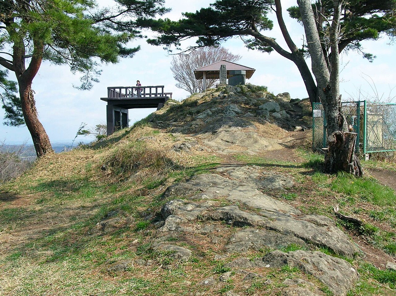 A timber viewing deck and a small roofed shelter on the rocky summit of Otakamori, framed by wind-bent pines