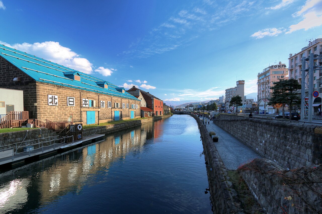 Stone warehouses reflected in the still water of the Otaru Canal on a clear day