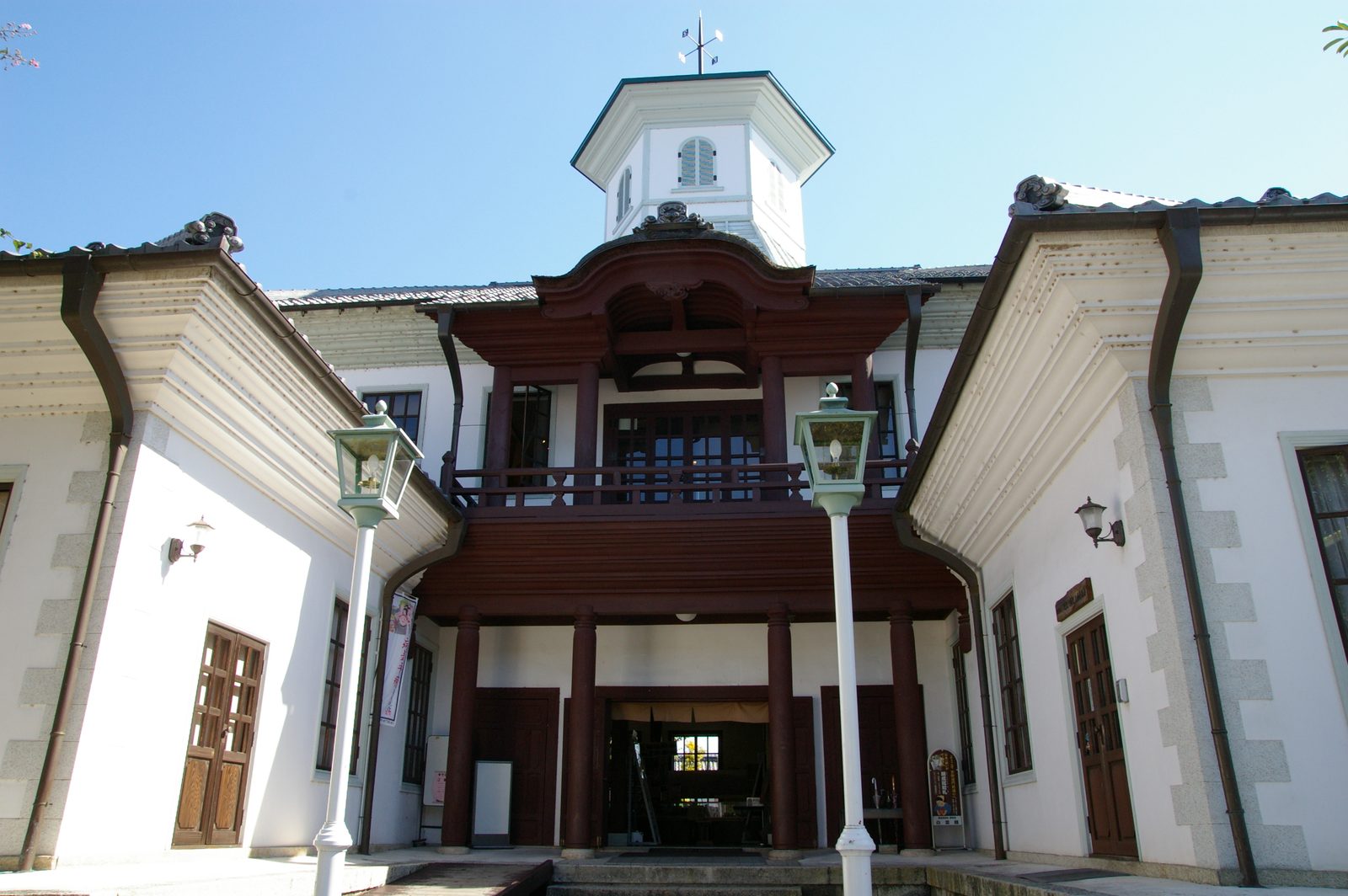 The white-walled Hakuunkan seen from the front under a blue sky, a Western-style building with a small octagonal tower and a reddish-brown wooden balcony