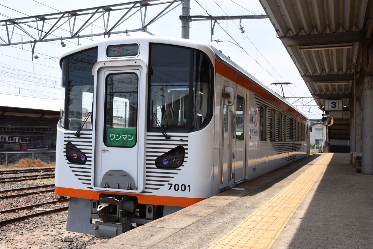 A white and orange Ichibata Electric Railway seven-thousand-series car waiting at the platform