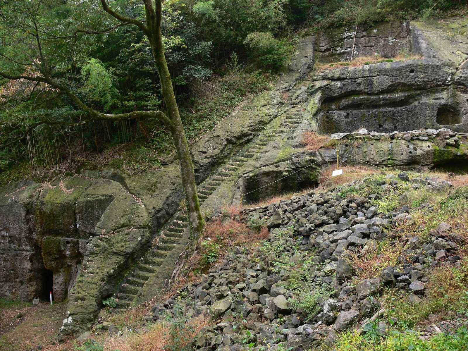 Mossy stone steps cut into the rock beside rubble on the wooded hillside near the Kamaya Mabu mine entrance