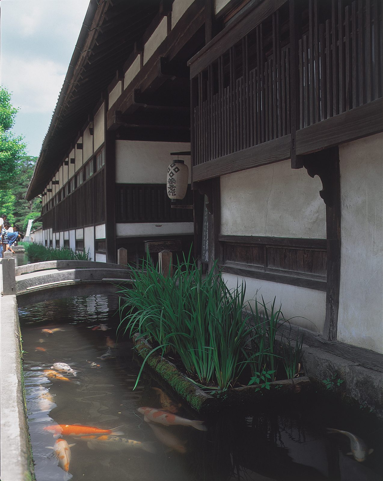 A lantern reading Yorokan hangs near a footbridge over the koi canal on Tonomachi street.