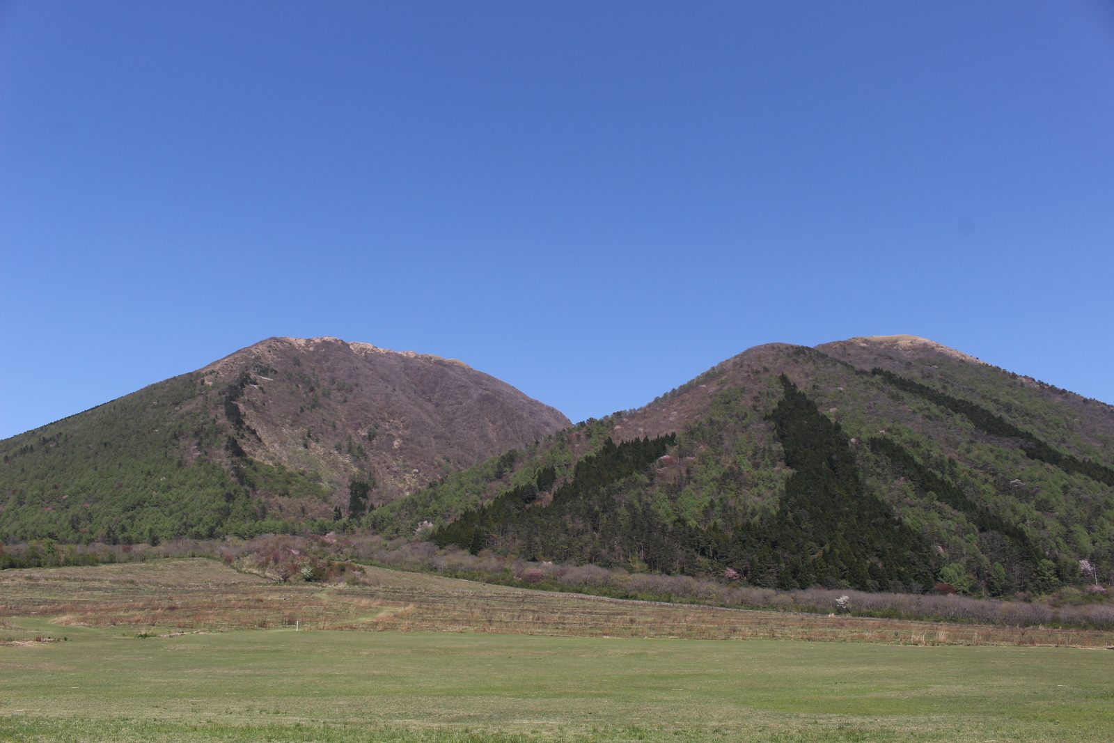 Twin peaks of Mount Sanbe rising above the open Nishi-no-hara grassland under a blue sky