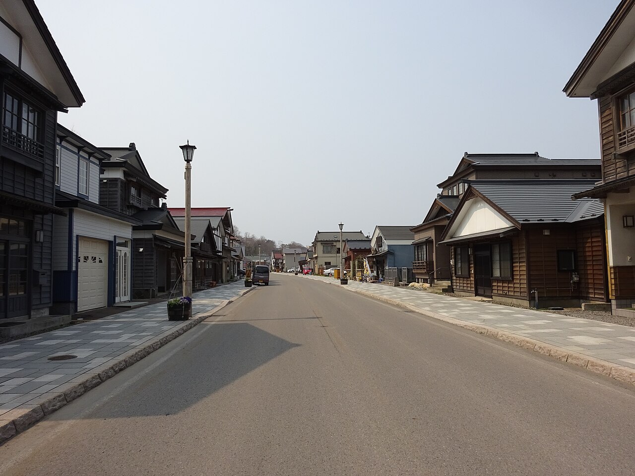 A quiet street lined with dark wooden merchant houses and a paved sidewalk on the Inishie Kaido, Esashi, Hokkaido