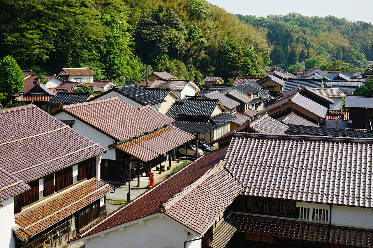 Tiled rooftops and old wooden townhouses of Omori in the Iwami Ginzan area, seen from above with forested hills behind