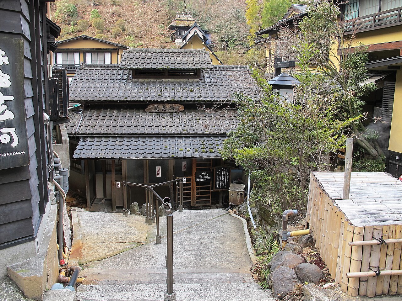 Dark tiled roofs and a stone stairway leading down between wooden buildings in Kurokawa Onsen