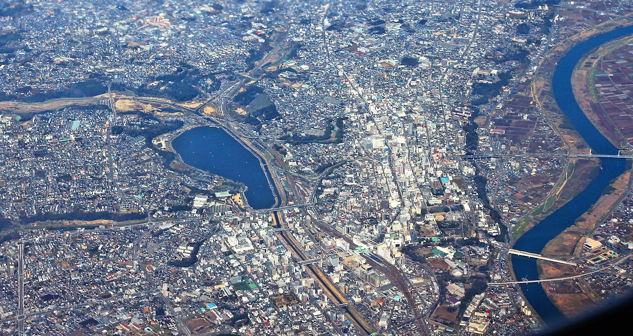 An aerial view of central Mito, with Lake Senba on the left, the town's streets in the middle and the Naka River curving along the right.