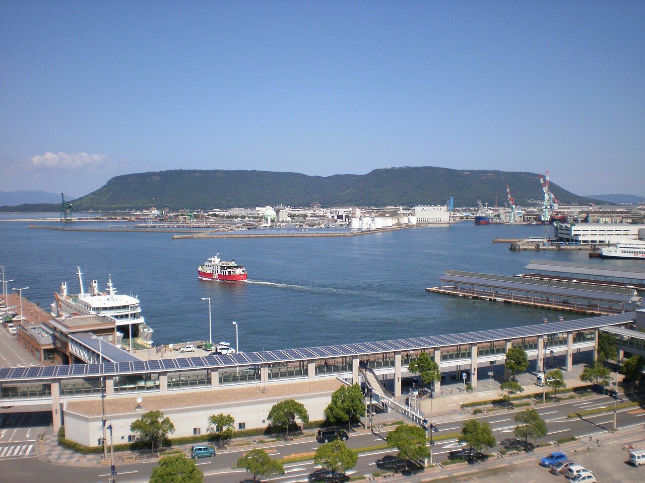 Takamatsu harbour with ferries and quays in the foreground and the long flat-topped ridge of Yashima rising across the water