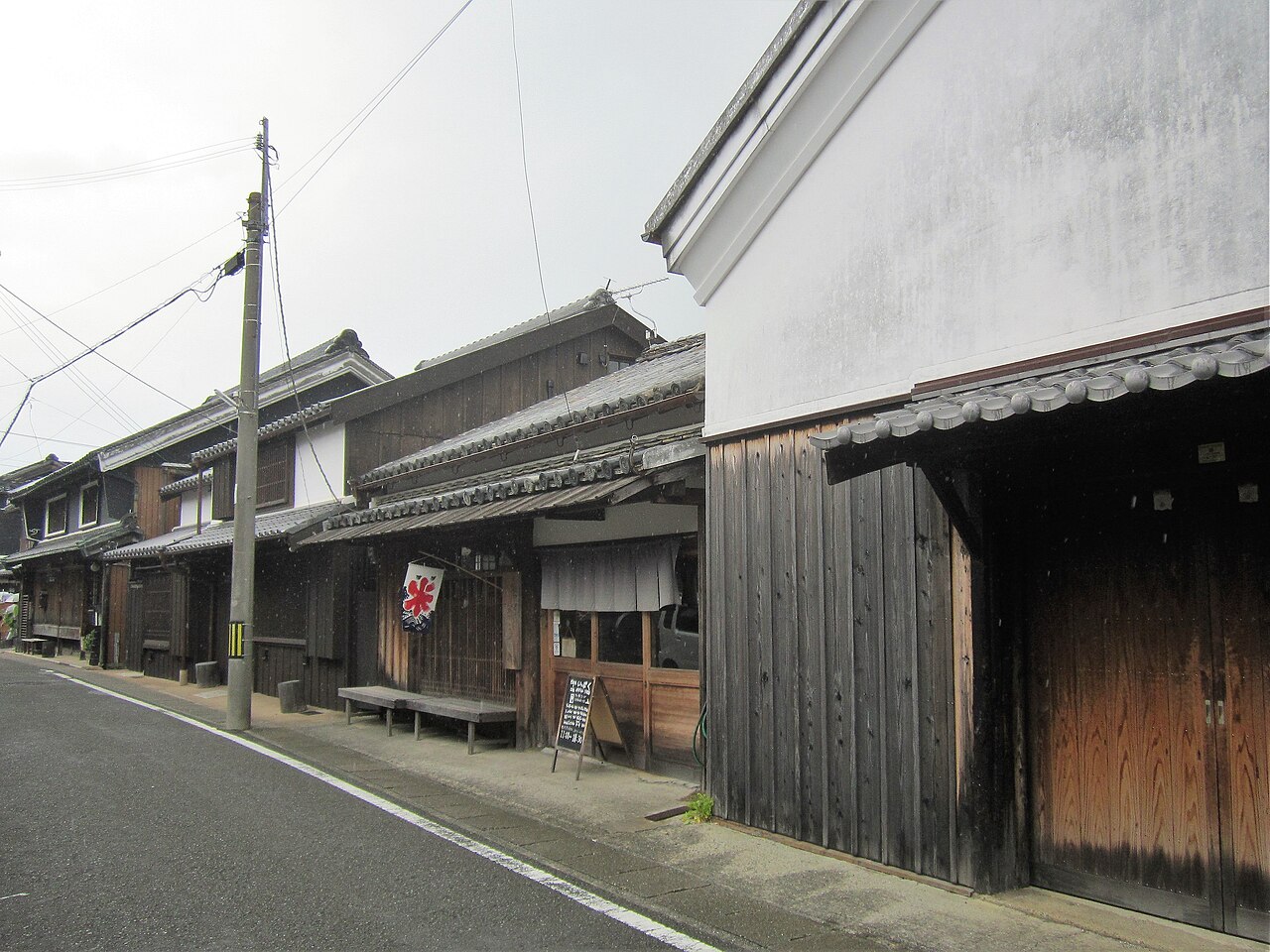 Old wooden townhouses and a white plaster storehouse along a quiet street in the Kitamachi area of Yuasa