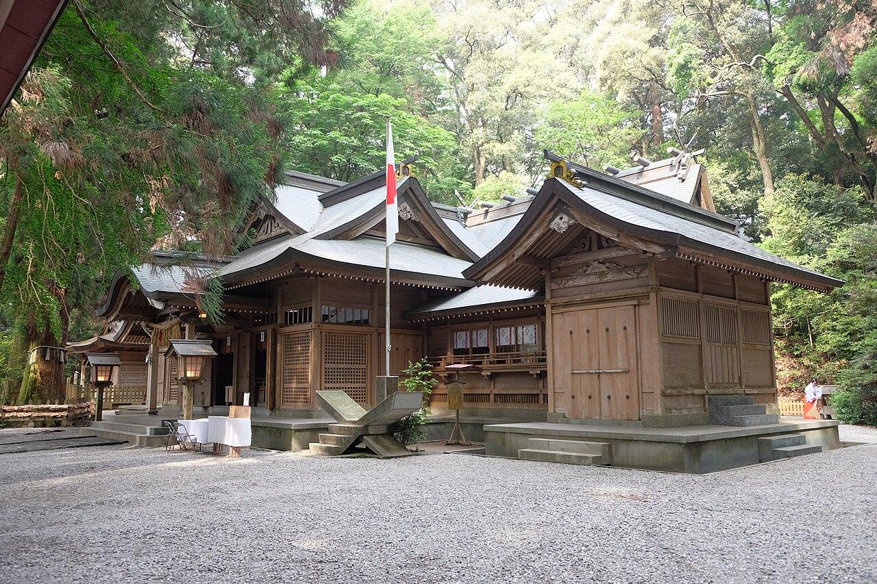 The worship hall of Takachiho Shrine standing among tall cedars.