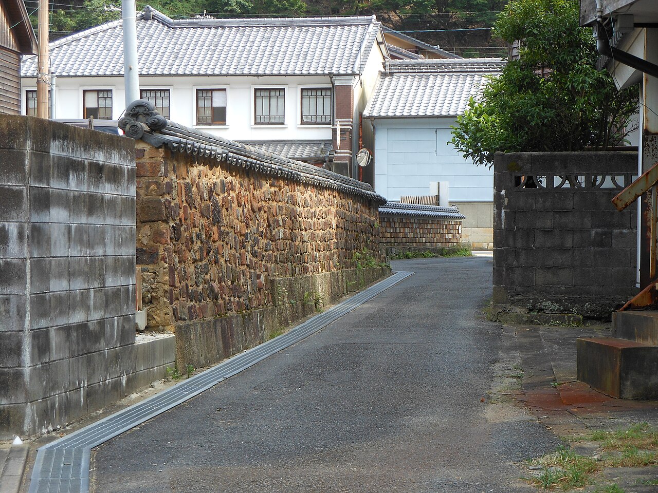 A lane in Arita's Kami-Kohei district, with a tonbai wall built from old kiln bricks and a white-walled house beyond