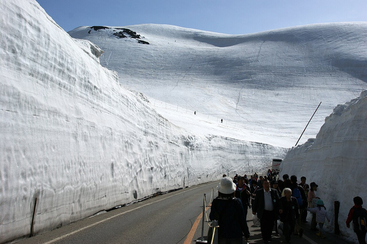 Visitors walking along a mountain road between towering walls of snow on the Tateyama Kurobe Alpine Route