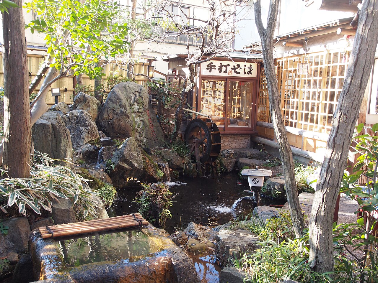 A handmade soba restaurant at Jindaiji Temple, with a water wheel turning beside a garden stream.