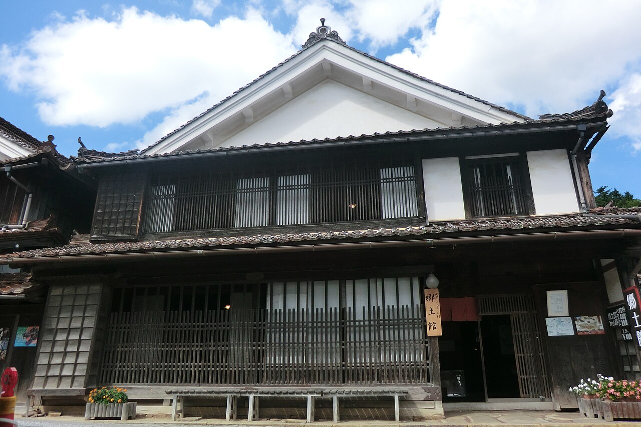 Two-storey Fukiya local museum building with a broad white gable, dark lattice windows and a vertical sign reading Kyodokan