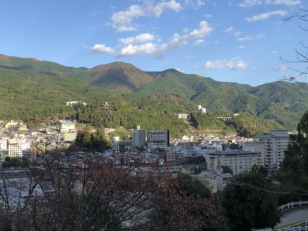 Hotels and houses of Gero Onsen spread below forested mountains on a clear autumn day