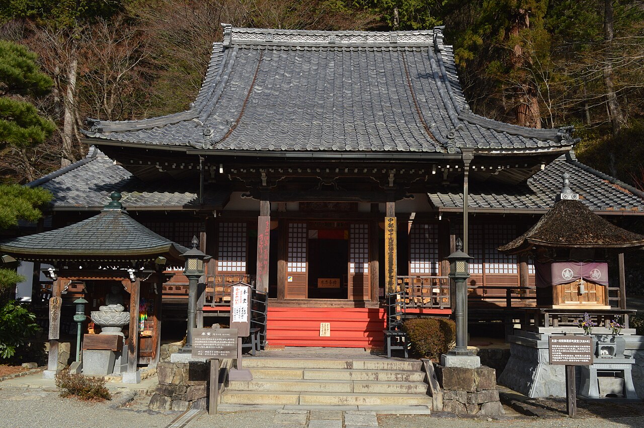 The tiled-roof main hall of Onsen-ji Temple with its stone steps and lanterns above Gero Onsen