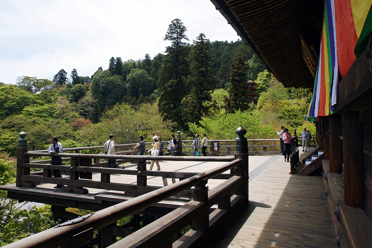 Visitors on the wooden stage of the main hall at Hasedera, looking out over forested hills