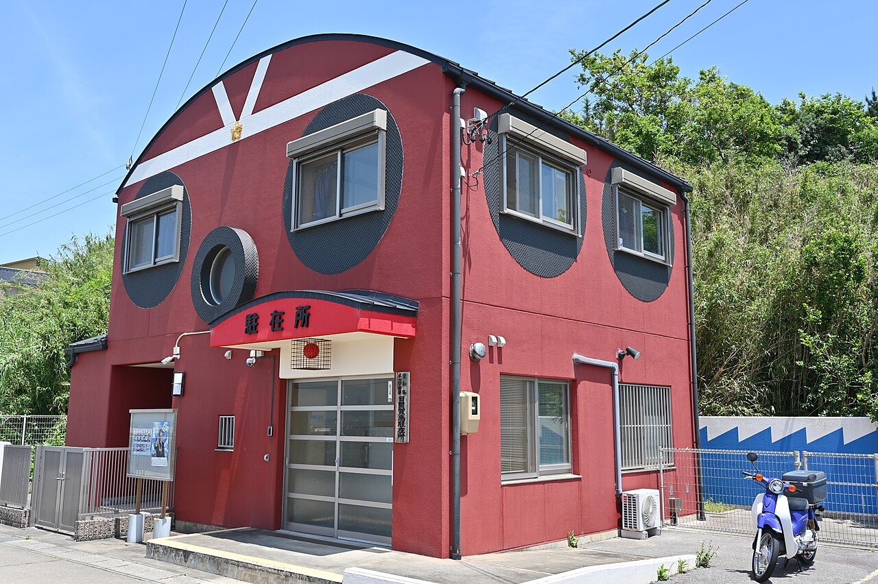 The red police box on Himakajima, its round dark window frames styled like the suckers of an octopus.