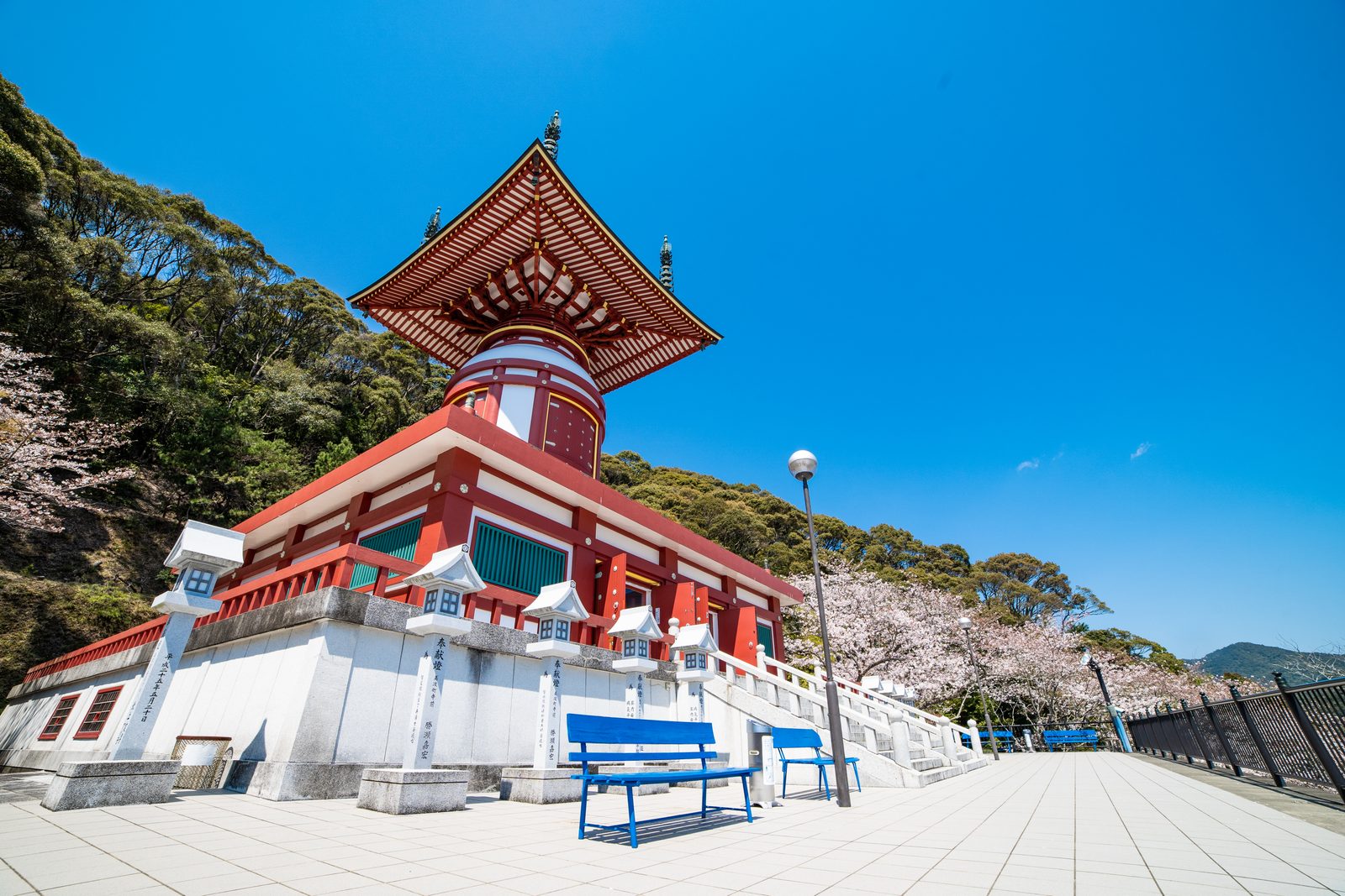 The red and white Yugito pagoda of Yakuoji on its stone terrace under a deep blue sky