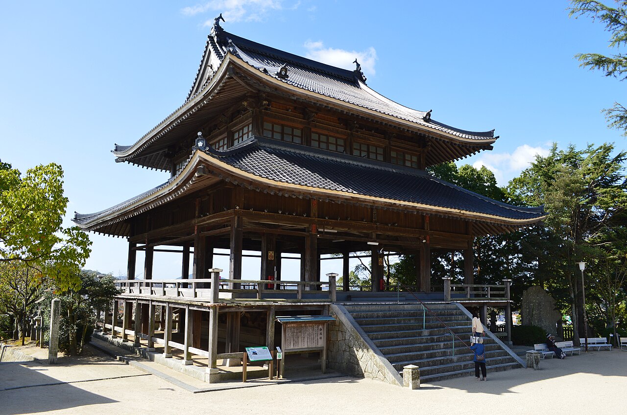 The Shunpuro, a two-tiered unpainted wooden pavilion with grey tiled roofs and a stone stairway, in the grounds of Hofu Tenmangu