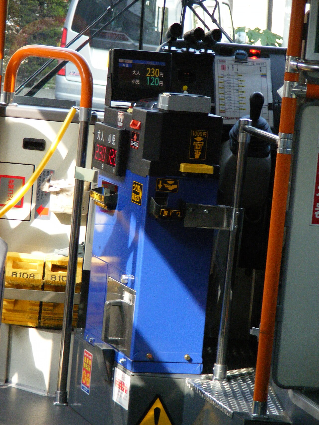 Blue fare box in a Japanese bus with a fare display showing adult 230 yen and child 120 yen, a banknote slot and a coin and change tray
