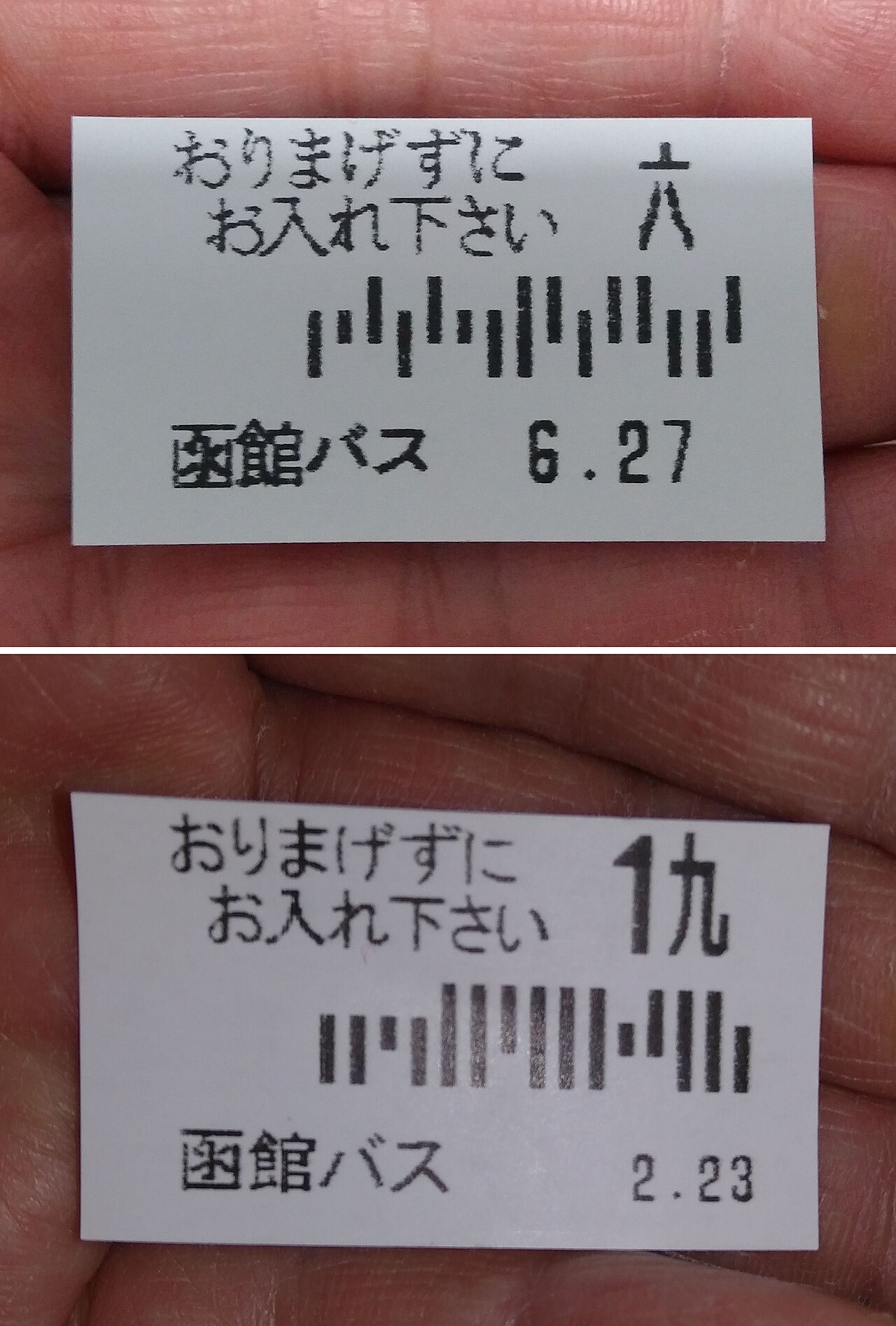 Two small paper numbered tickets from Hakodate Bus held in a hand, each printed with a ticket number, a barcode and a date