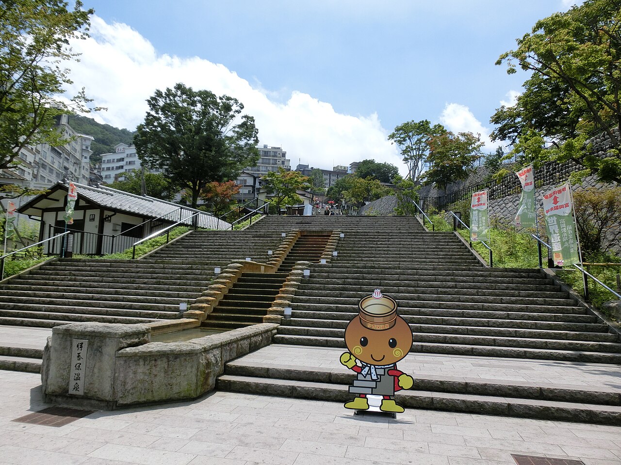 Stone steps of Ikaho Onsen under a blue summer sky, with water running down a channel in the middle of the steps.