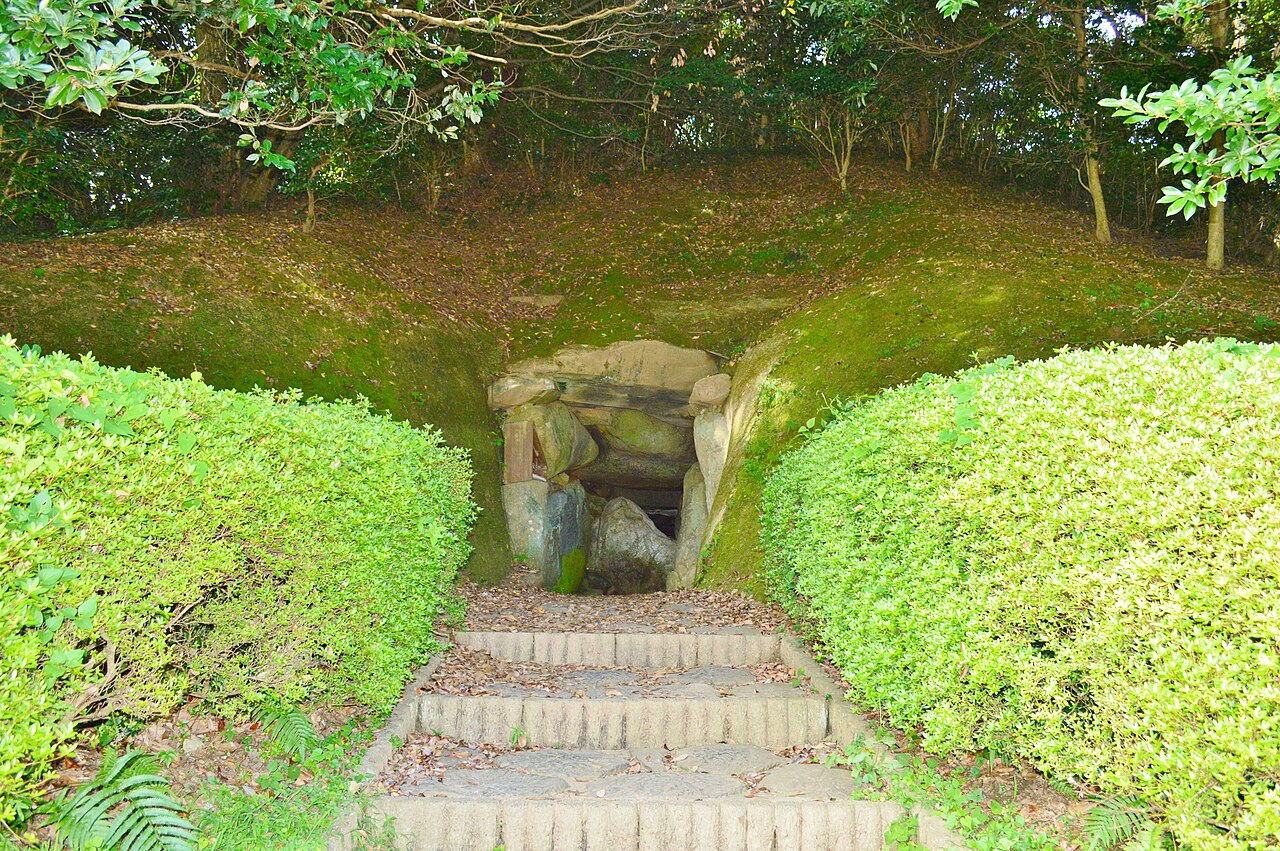 Stone steps between trimmed hedges leading up to the stone chamber entrance of Oni-no-iwaya burial mound on Iki Island.