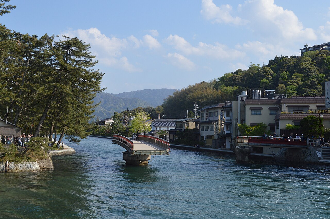 The red swing bridge over the Amanohashidate canal turned open beside pine-covered banks
