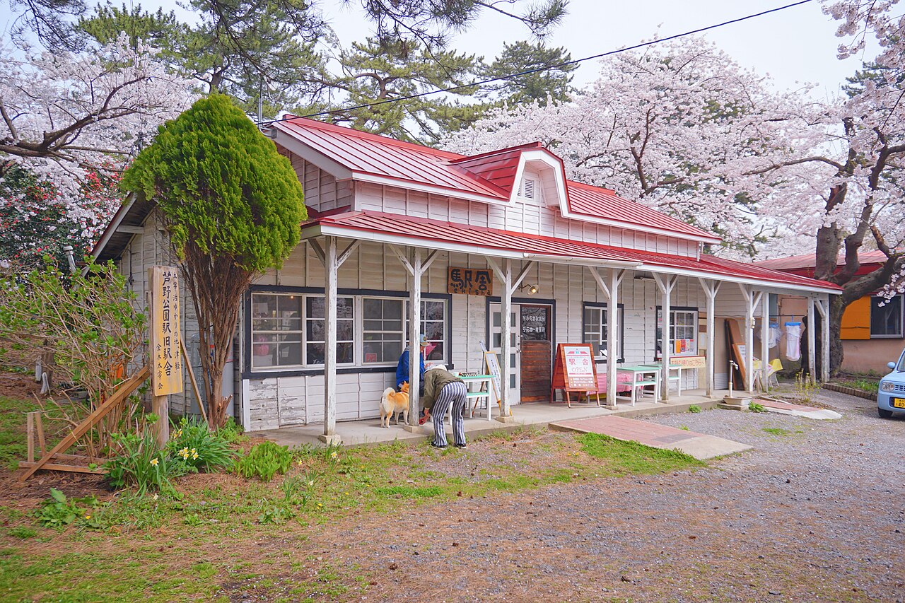 The red-roofed former Ashino Park station building on the Tsugaru Railway, surrounded by cherry blossoms