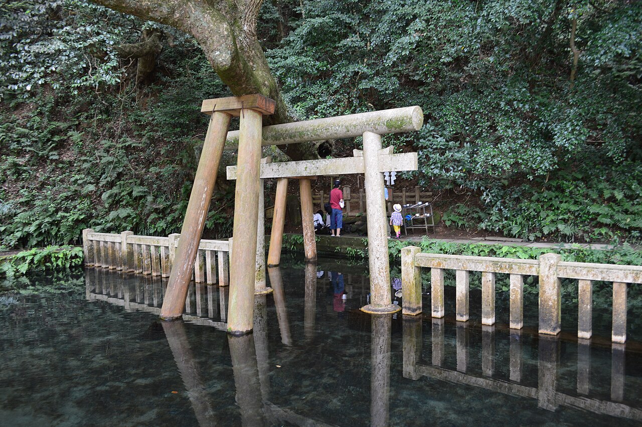 The timber torii standing in the clear spring water of Mitarashi Pond at Kashima Jingu, reflected on the surface